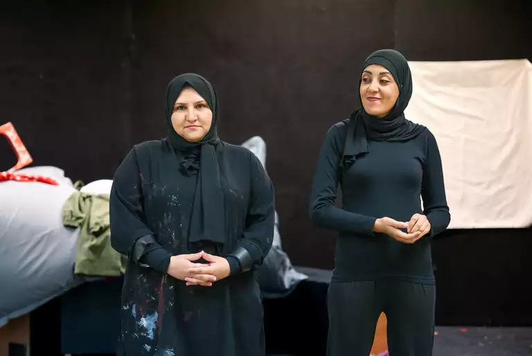 Die Schauspielerinnen Hana Abdelnabi und Hend Abu Hassanein stehen im Vordergrund und schauen ins Publikum.