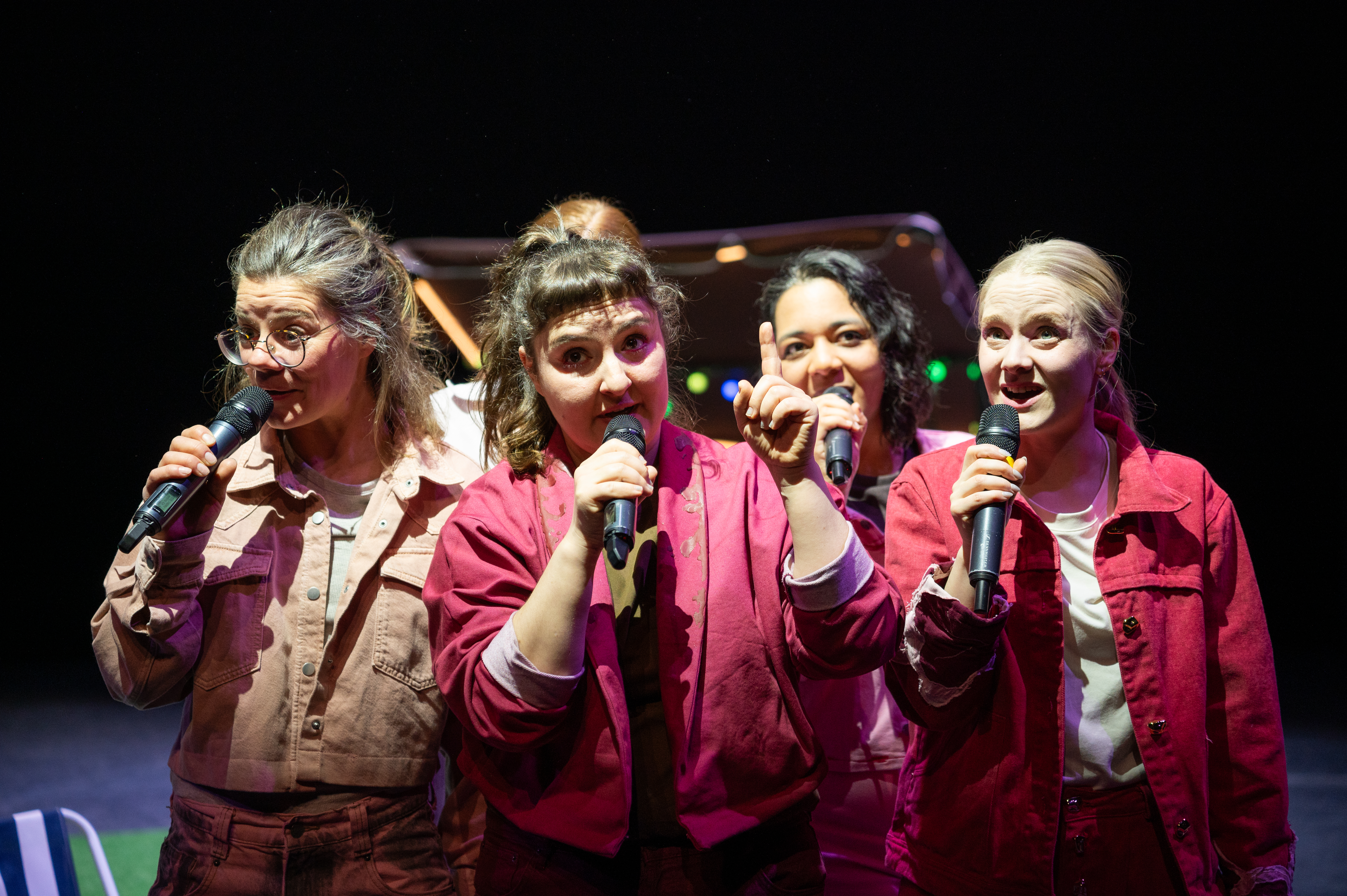 5 Fraun in fleischfarbenen Kostümen sprechen in Mikrofone, eine Person hebt den Zegefinger.